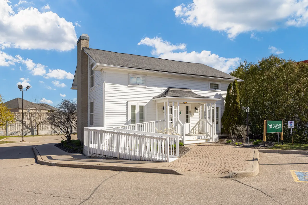 The white clapboard house at 75 Dawson Manor Blvd, with its porch, its ramp and the BWell sign