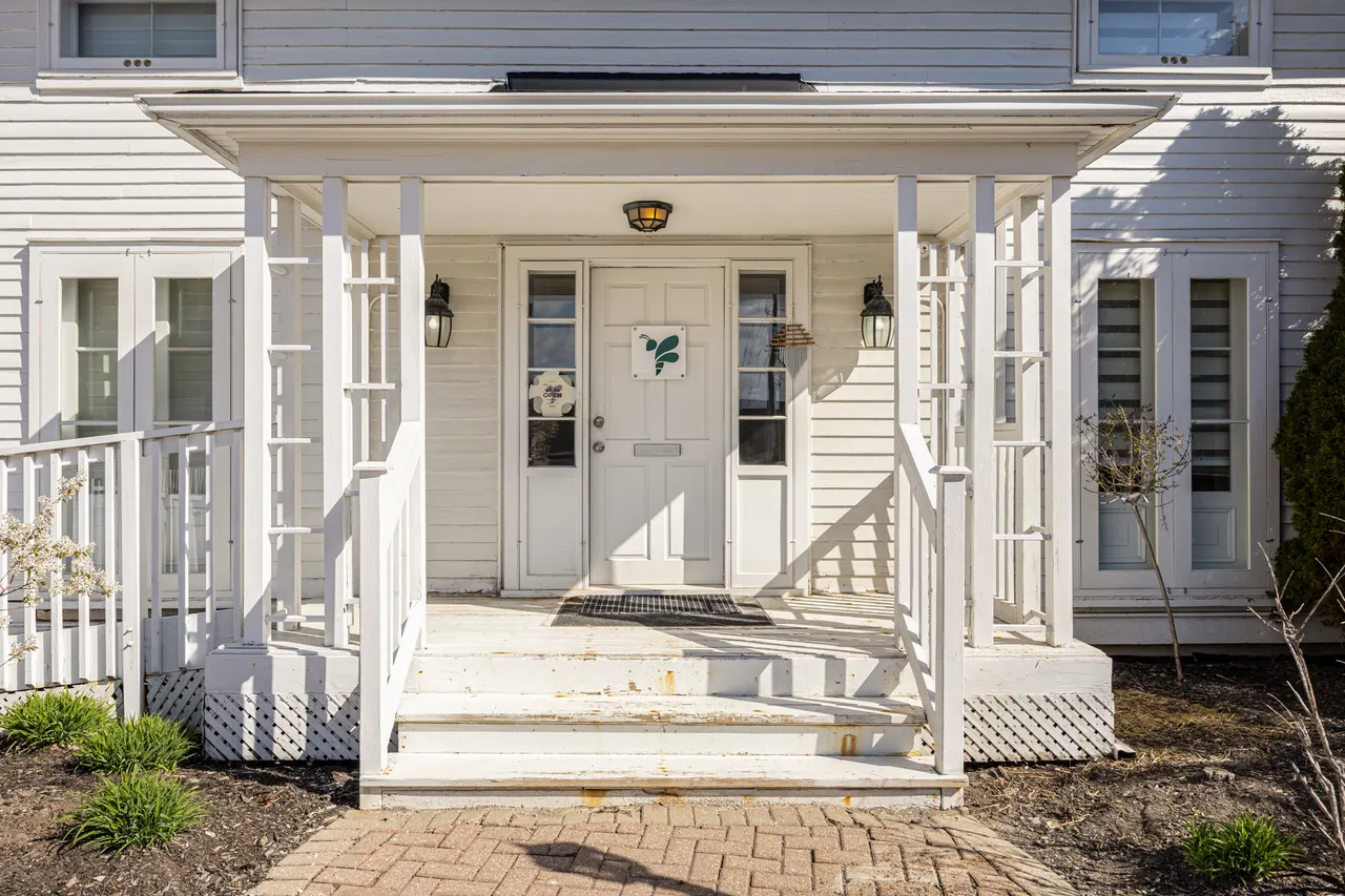 The porch and front door of BWell Lounge, with a bee decal on the door