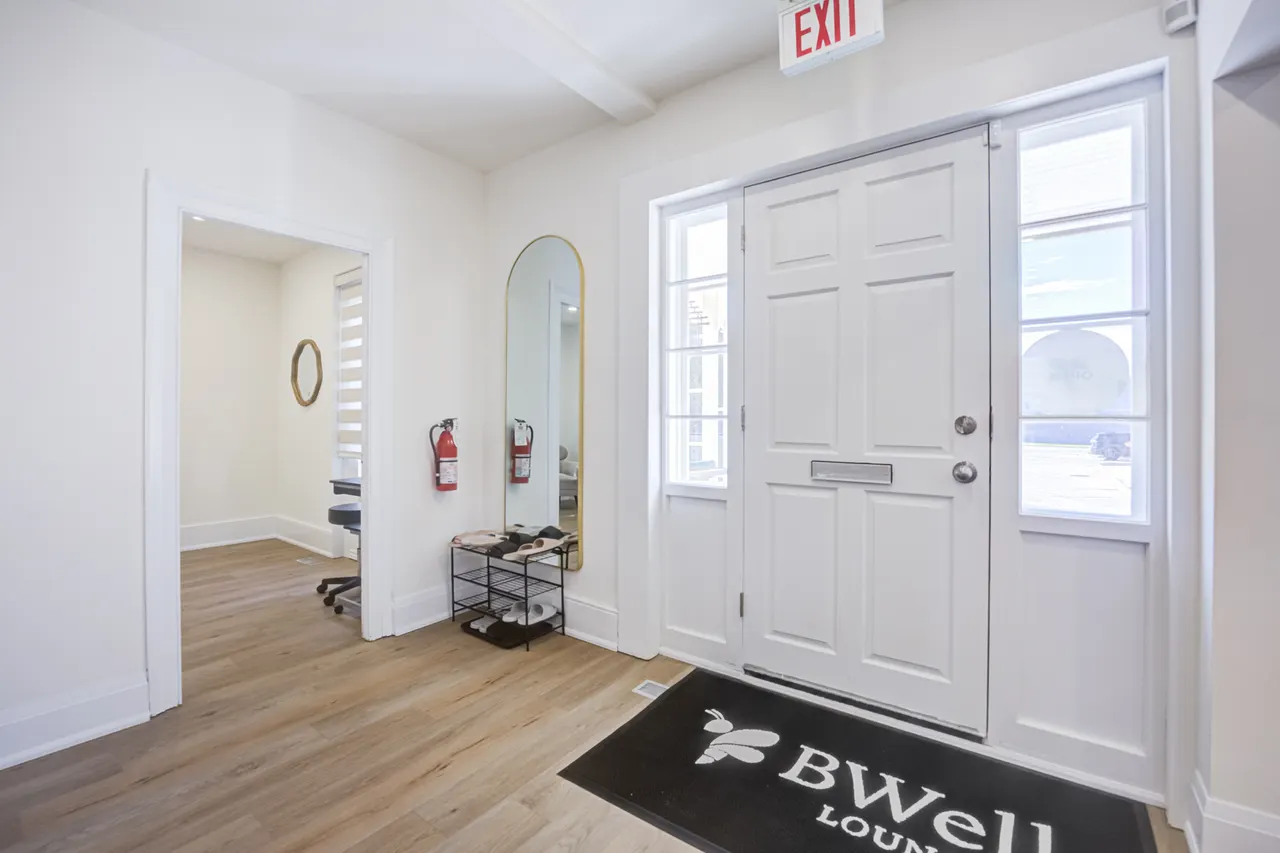 The entry hall with the BWell doormat and a brass arched mirror