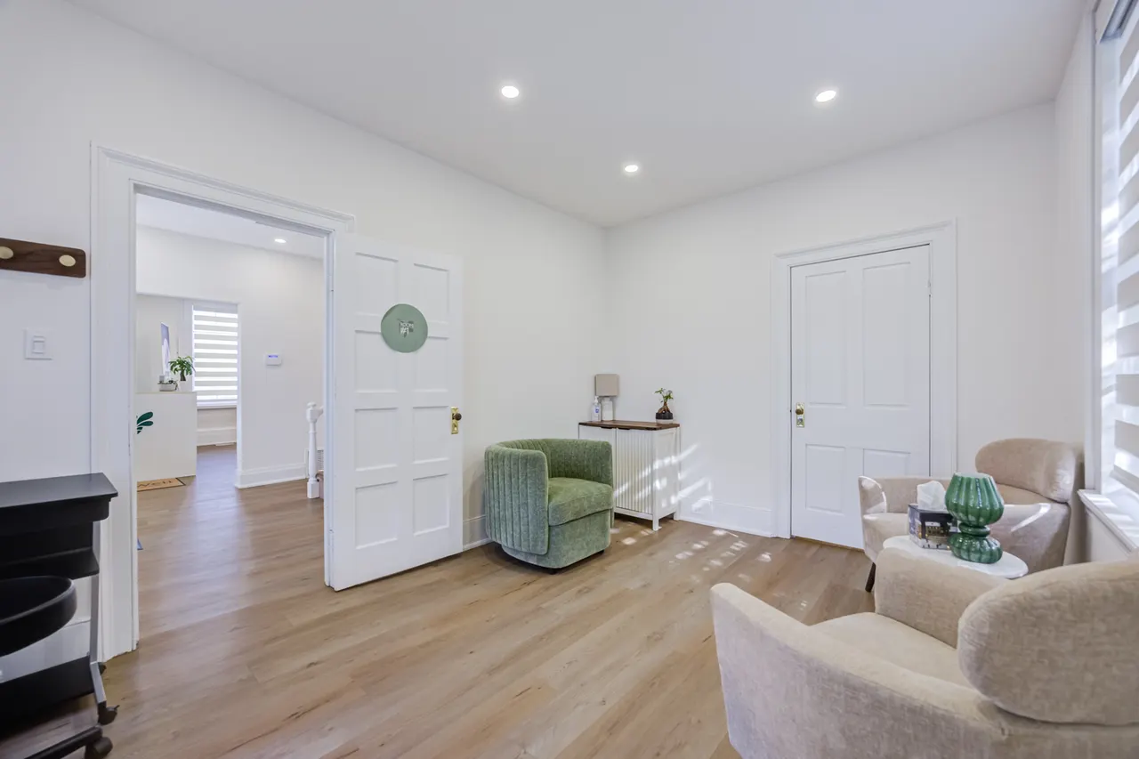 A room at BWell Lounge with a green velvet armchair between an open door and a closed white door