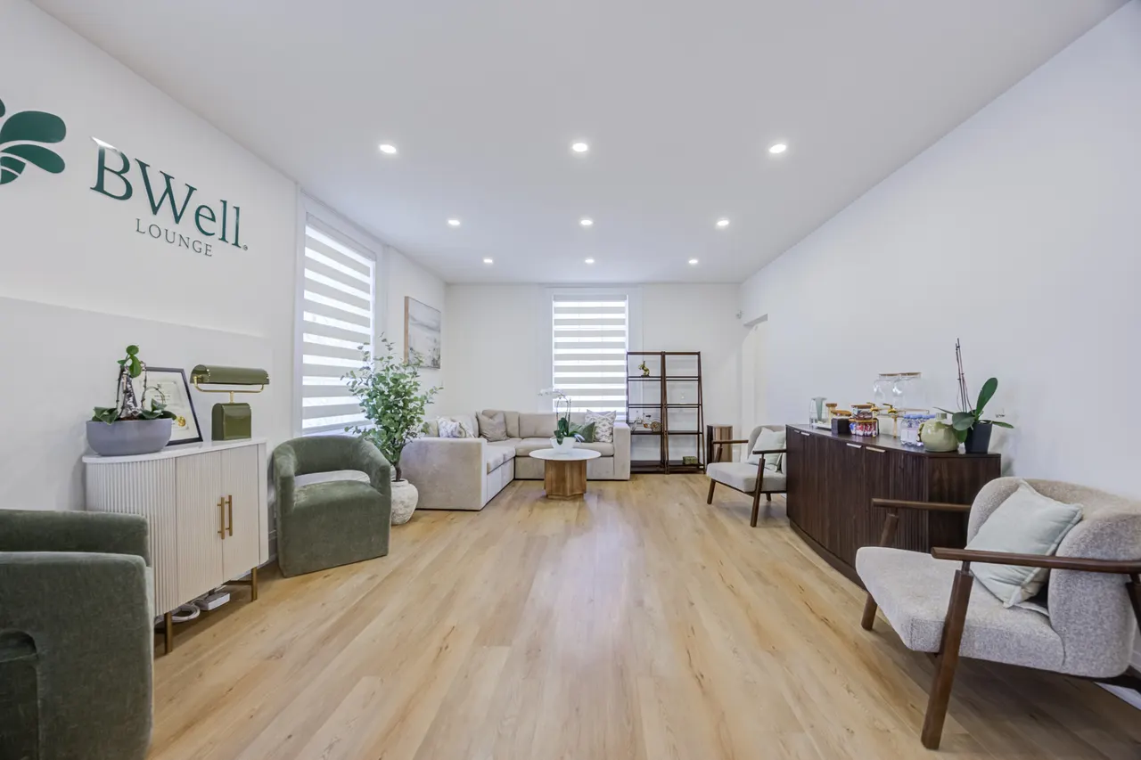 The lounge at BWell Lounge: green armchairs, a cream sofa and the BWell Lounge sign on the wall