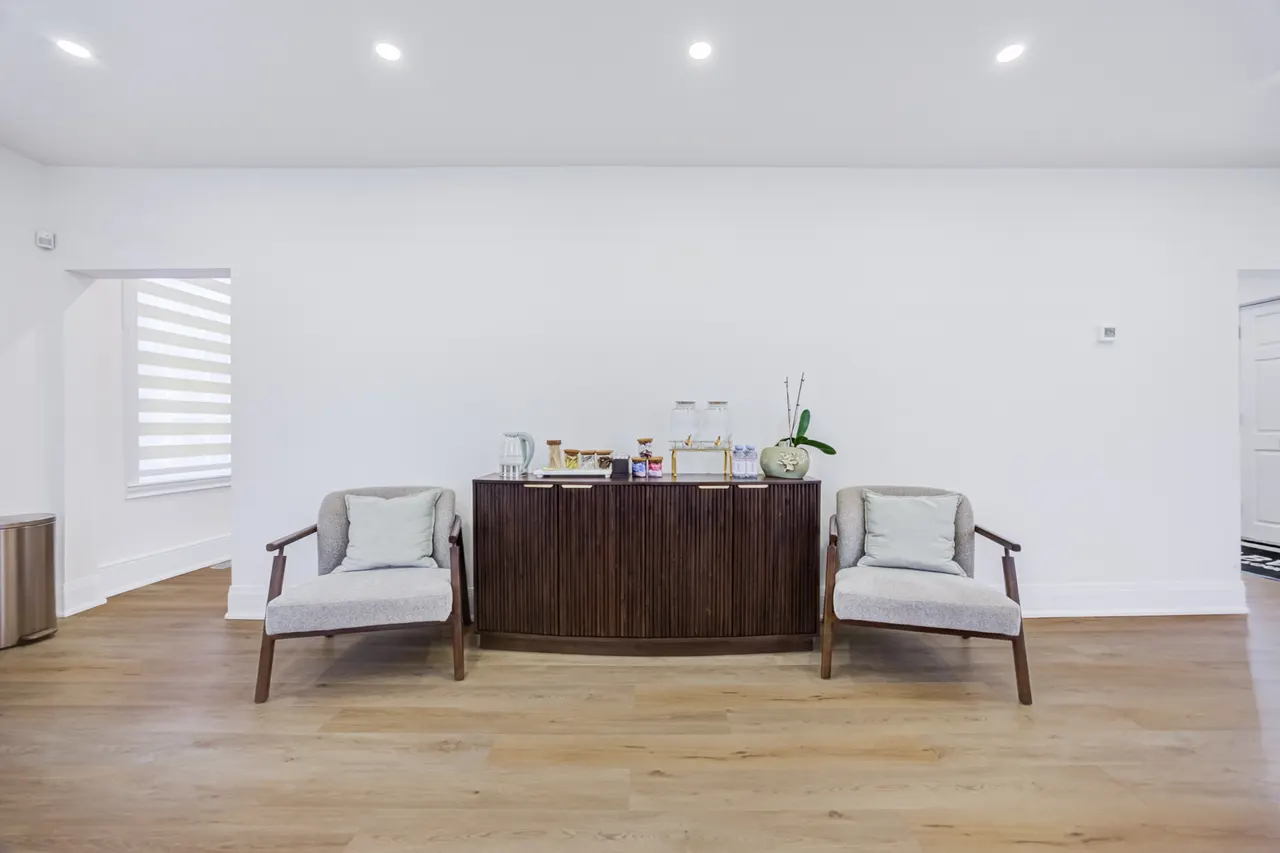 A walnut sideboard with a tea station between two chairs