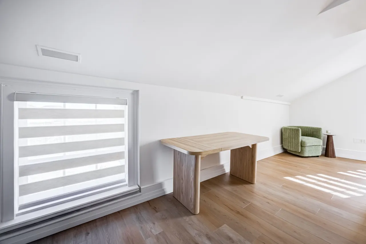 A bright upstairs room at BWell Lounge with a wooden desk and a green chair