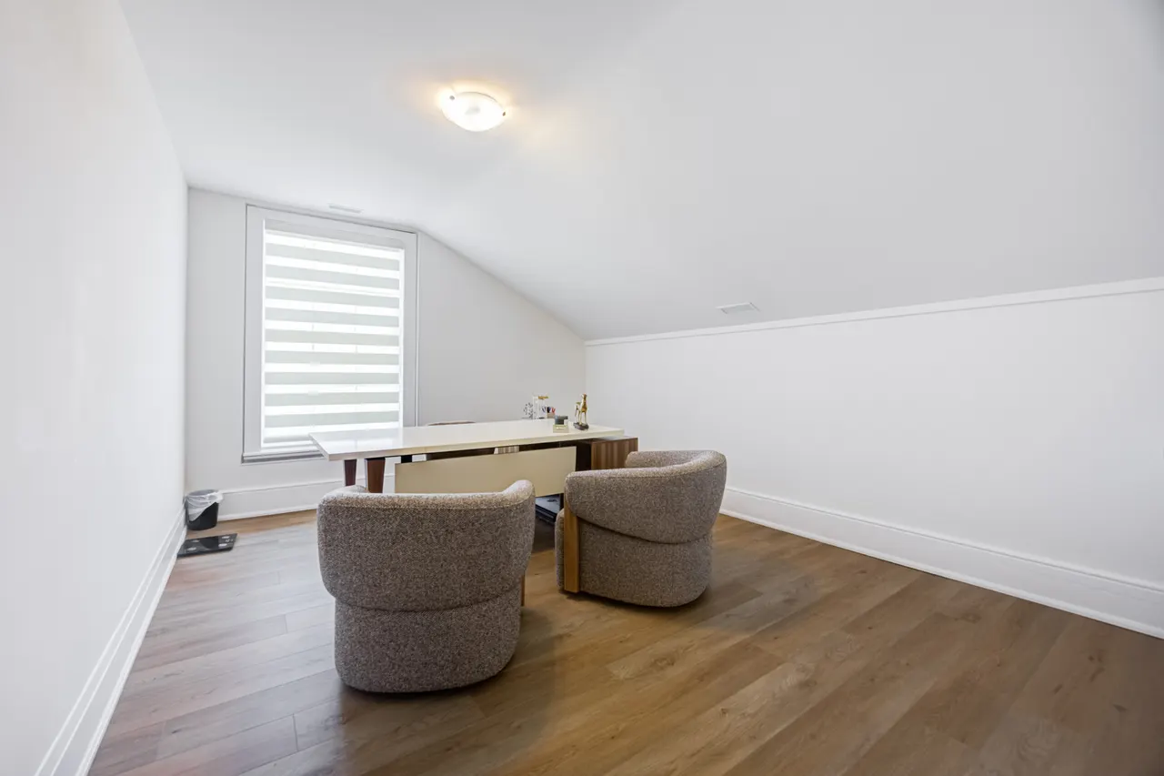 An office at BWell Lounge with a sloped ceiling, a desk and two taupe bouclé chairs