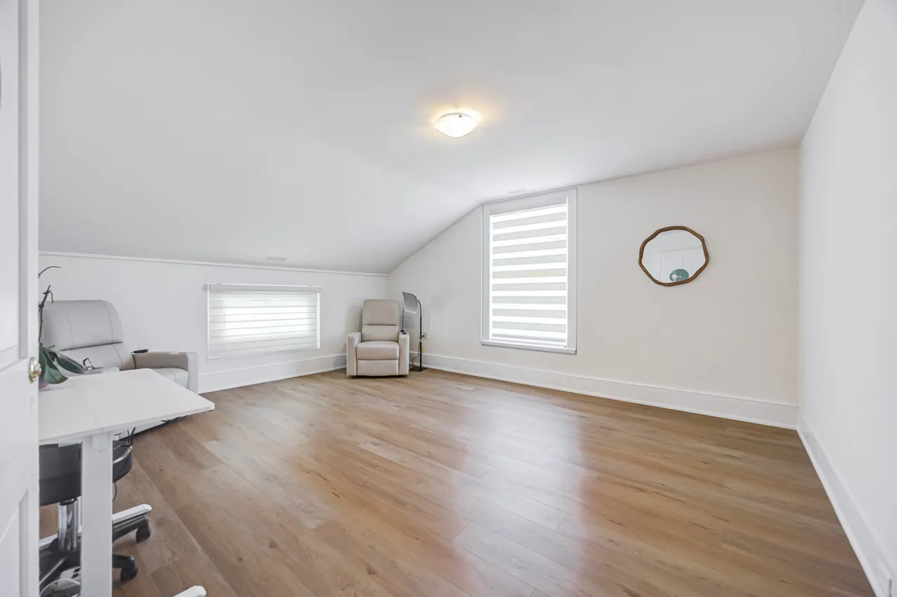 A bright upstairs room at BWell Lounge with cream recliner chairs, a desk and a window
